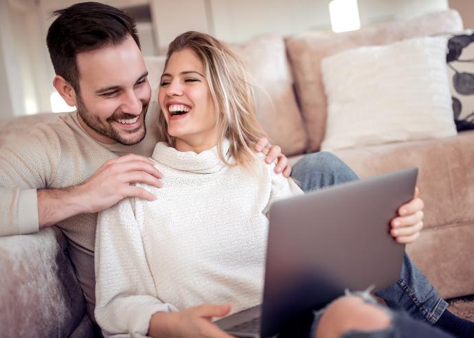2 mensen, man en vrouw met laptop , lachen, met laptop op de schoot